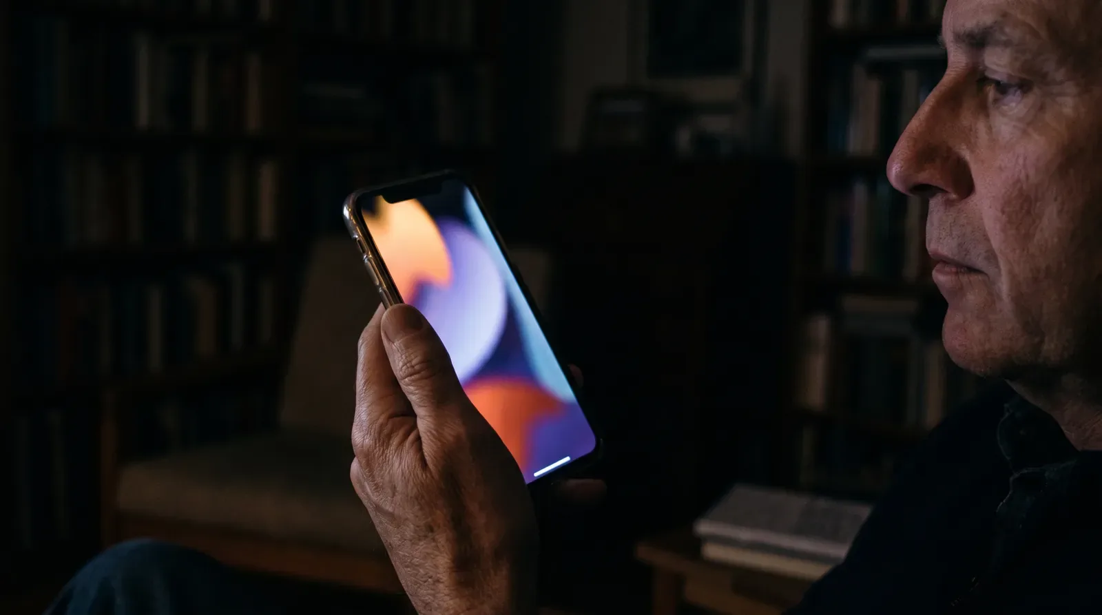 A hand holding a phone, reading an article in a dark room at night